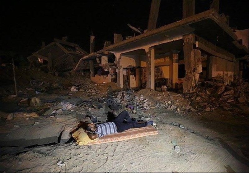 خوابیدن جوان فلسطینی مقابل ویرانه‌های منزلش در جنگ غزه + عکس