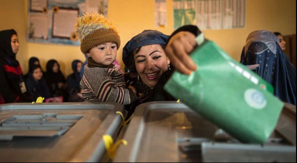 یک زن افغان به همراه کودک خود در مزار شریف، رأی خود را درون صندوق اخذ رأی می اندازد. دور اول انتخابات ریاست جمهوری افغانستان/ 5 آپریل 2014