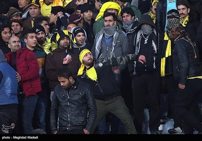 یکی از تماشاگران تیم فوتبال سپاهان در حال پرتاب یخ به سمت جایگاه تماشاگران تیم فوتبال پرسپولیس