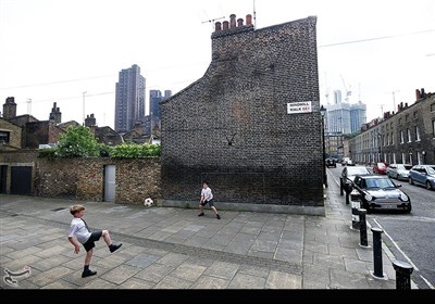 دو کودک انگلیسی در حال بازی فوتبال در پیاده روی خیابان های لندن