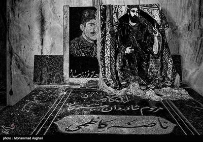 شهرستان اندیکا.استان خوزستان. تصویر شهید فاضل کاظمی بر روی قبر برادرش در کنار قبر شهید.
