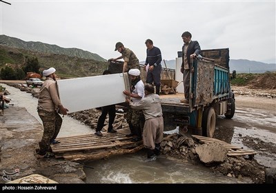 روحانیون حوزه علمیه آقا ضیاءالدین اراک در حال انتقال لوازم منزل سیل زدگان در روستای ملاوی از توابع بخش مرکزی شهرستان پلدختر به کامیون هستند