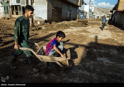 یکی از نیروهای سپاه پاسداران کودک سیل زده پلدختری را جابجا می کند