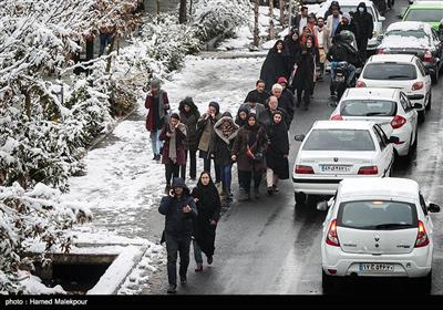 پیاده‌روی شهروندان تهرانی در خیابان ولیعصر در روز برفی پایتخت به دلیل عدم تأمین وسایل نقلیه عمومی