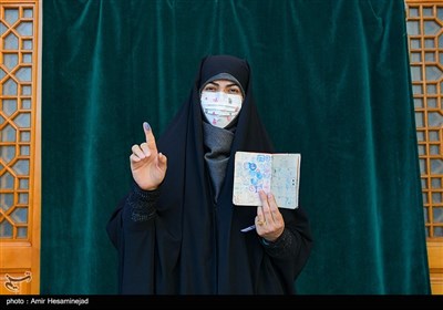 A woman in a medical mask posed for a picture after voting in Qom