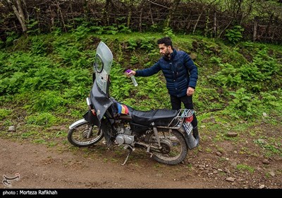 مبین شریفی قبل از حرکت به سمت مدرسه موتور خود را با مایع ضد عفونی کننده اسپری میکند تا از انتقال احتمالی ویروس به روستا جلوگیری کند.