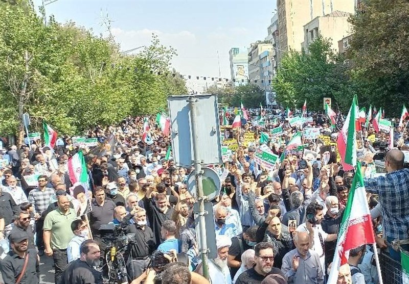 پرچم سه رنگ جمهوری اسلامی ایران در دست راهپیمایان تهرانی