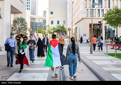 فردی با پرچم فلسطین در محله مشریب شهر دوحه پیاده روی میکند. بسیاری از مسلمانان در حمایت از مردم فلسطین پرچم این کشور را در طول مسابقات جام جهانی با خود حمل میکنند.