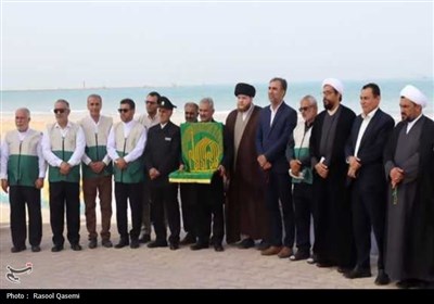 اهتزاز پرچم حرم رضوی به دست خدام در سواحل خلیج فارس بوشهر