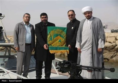 اهتزاز پرچم حرم رضوی به دست خدام در سواحل خلیج فارس بوشهر